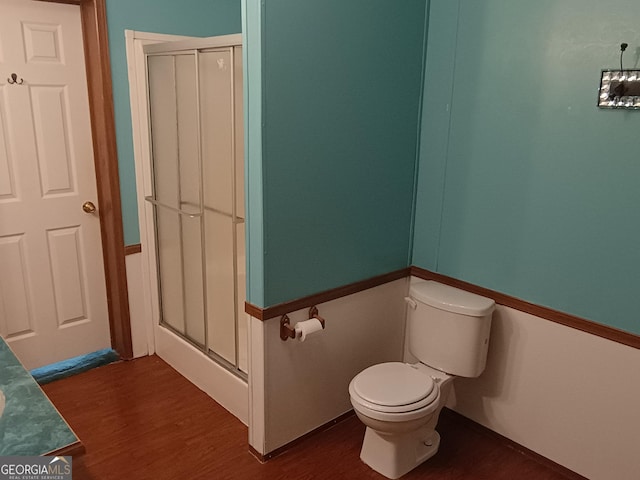 bathroom featuring hardwood / wood-style flooring, toilet, and an enclosed shower