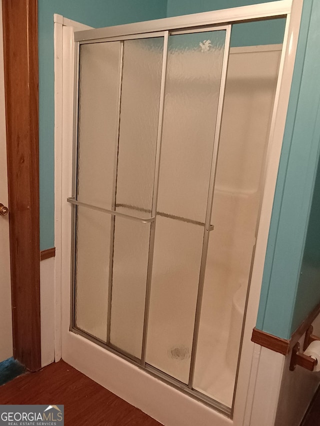 bathroom with wood-type flooring and a shower with shower door