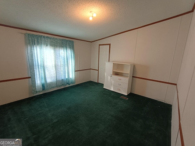 empty room with vaulted ceiling, ornamental molding, a textured ceiling, and dark colored carpet