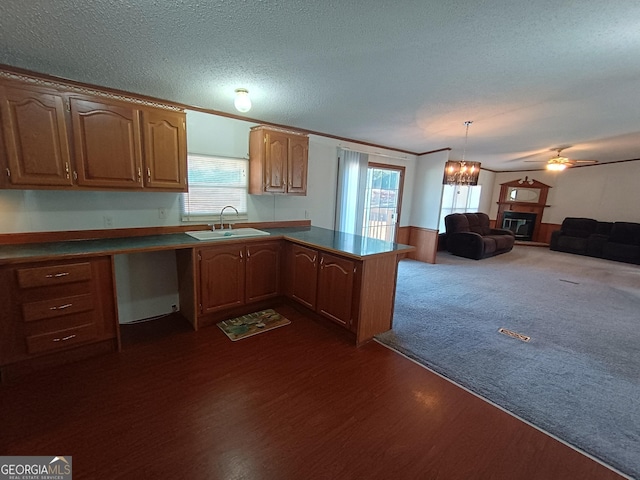 kitchen with kitchen peninsula, a textured ceiling, white dishwasher, sink, and decorative light fixtures