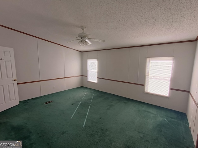 unfurnished room with a textured ceiling, dark carpet, ceiling fan, and a healthy amount of sunlight