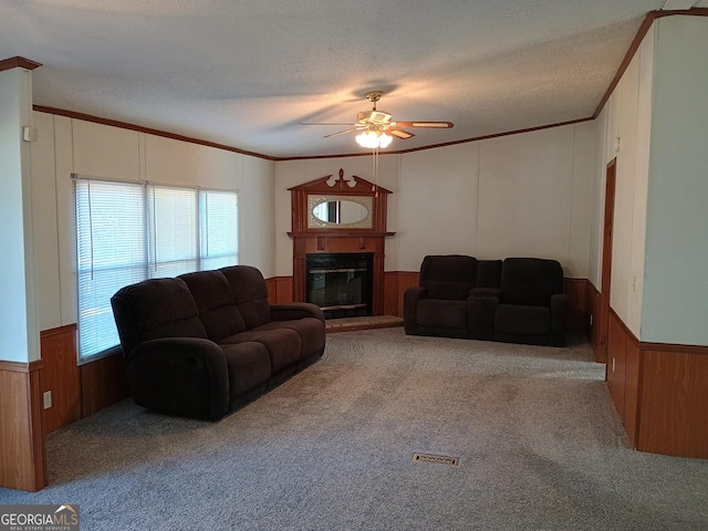 living room featuring a textured ceiling, light colored carpet, ceiling fan, and ornamental molding