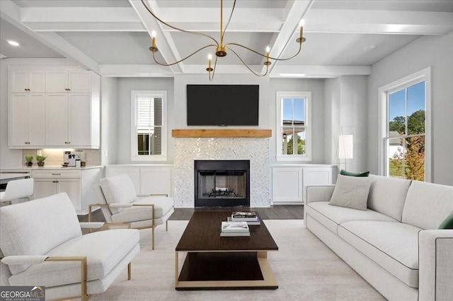 living room featuring light wood finished floors, beamed ceiling, a fireplace, and a healthy amount of sunlight