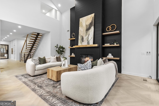 living room featuring a towering ceiling, a fireplace, and light parquet floors