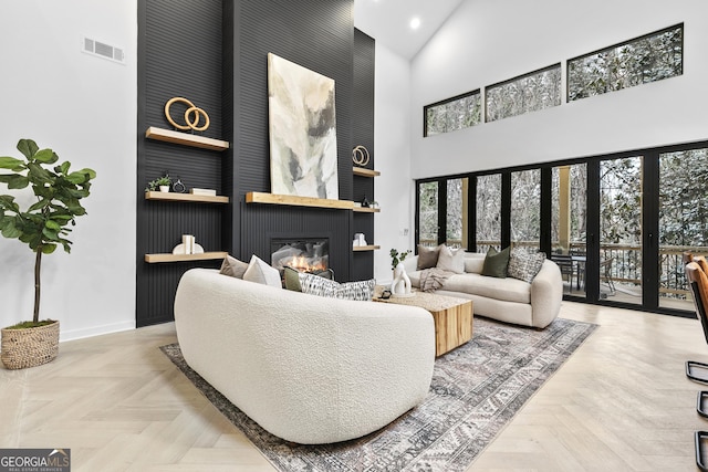 living room featuring a large fireplace, a towering ceiling, and parquet flooring