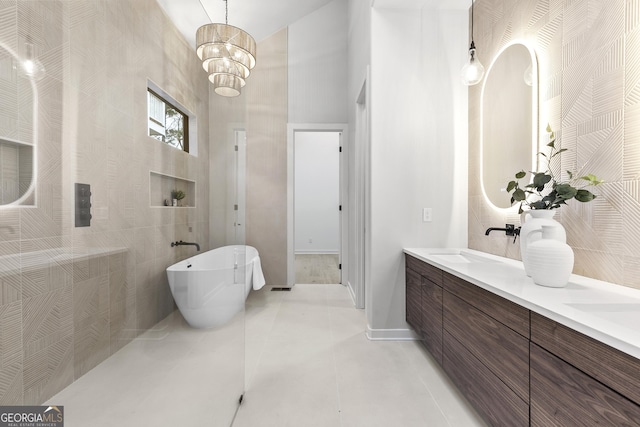 bathroom with a washtub, vanity, a high ceiling, and a notable chandelier