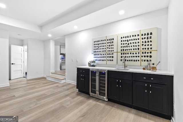 bar with light wood-type flooring, sink, and wine cooler