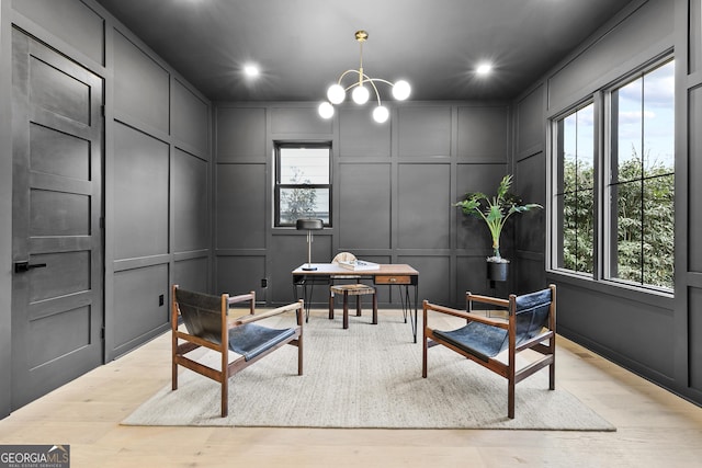 living area featuring light hardwood / wood-style floors, a healthy amount of sunlight, and a notable chandelier