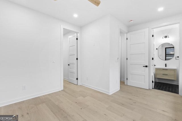 unfurnished bedroom featuring ensuite bathroom and light hardwood / wood-style floors