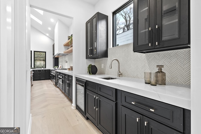 kitchen featuring sink, beverage cooler, high end stainless steel range oven, tasteful backsplash, and light stone counters