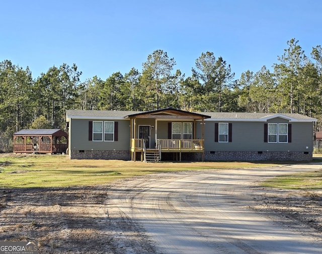 manufactured / mobile home with covered porch, a front yard, and a carport