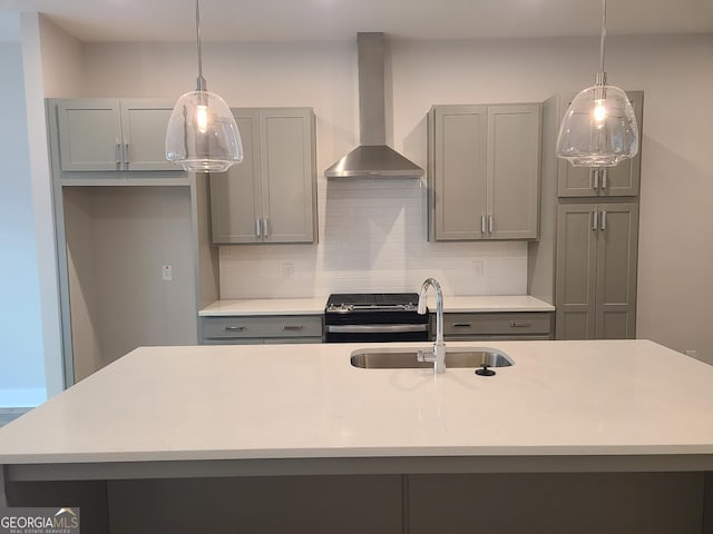 kitchen featuring gray cabinetry, hanging light fixtures, wall chimney exhaust hood, and sink