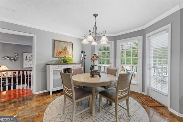 dining area with a textured ceiling, crown molding, and a notable chandelier