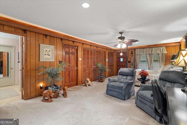 carpeted living room with ceiling fan and wooden walls