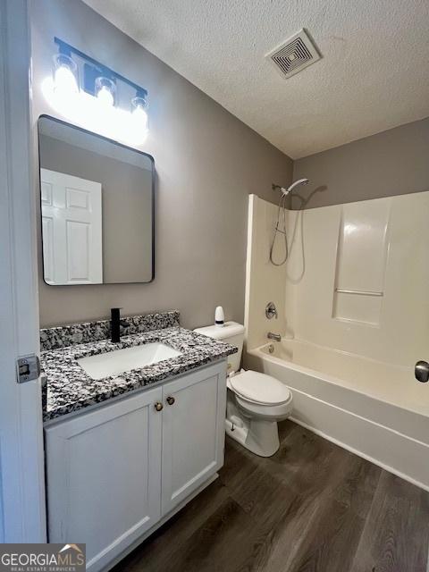 full bathroom featuring shower / bath combination, vanity, a textured ceiling, hardwood / wood-style floors, and toilet