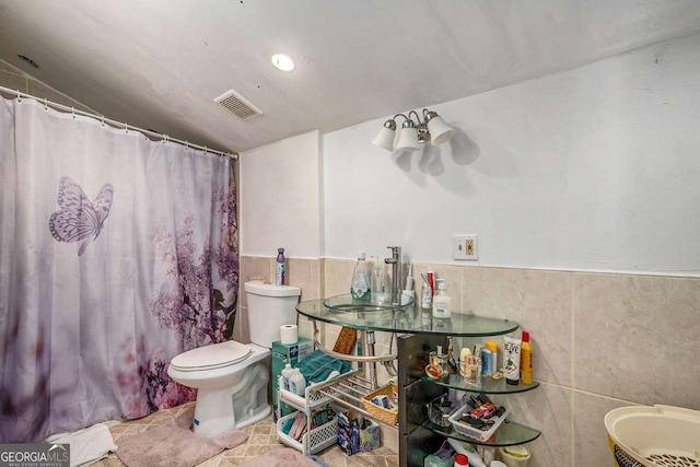 bathroom featuring toilet and tile walls