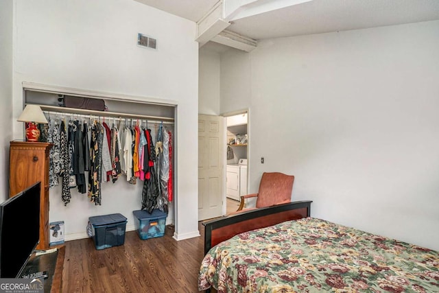 bedroom with a closet, dark wood-type flooring, lofted ceiling with beams, and washer and dryer