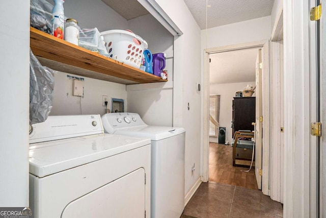 washroom featuring dark tile patterned floors, a textured ceiling, and washer and clothes dryer