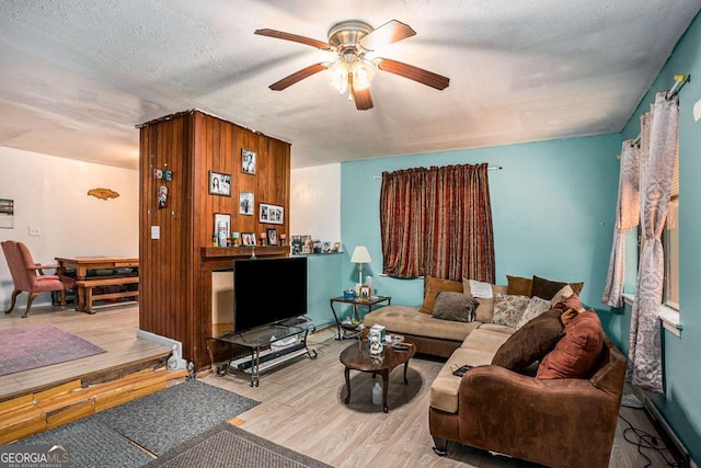 living room featuring ceiling fan, a textured ceiling, and light wood-type flooring