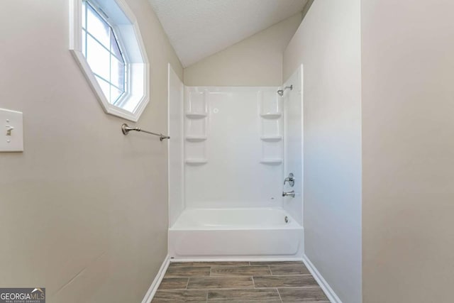 bathroom featuring shower / tub combination, a textured ceiling, and vaulted ceiling