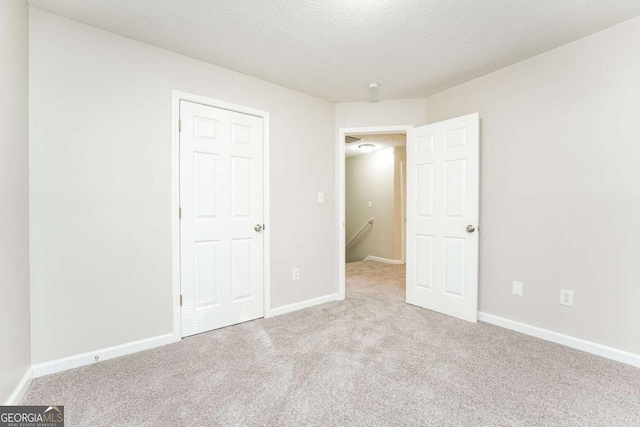 unfurnished bedroom featuring a textured ceiling and light colored carpet