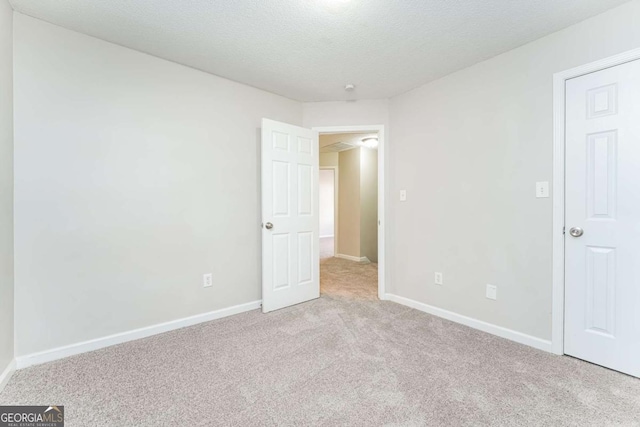 spare room with light colored carpet and a textured ceiling