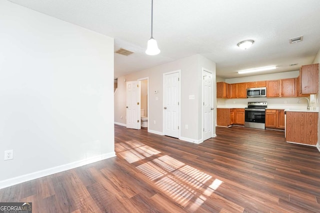 kitchen with sink, dark hardwood / wood-style floors, a textured ceiling, appliances with stainless steel finishes, and decorative light fixtures