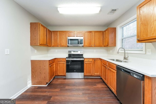 kitchen with appliances with stainless steel finishes, dark hardwood / wood-style floors, and sink