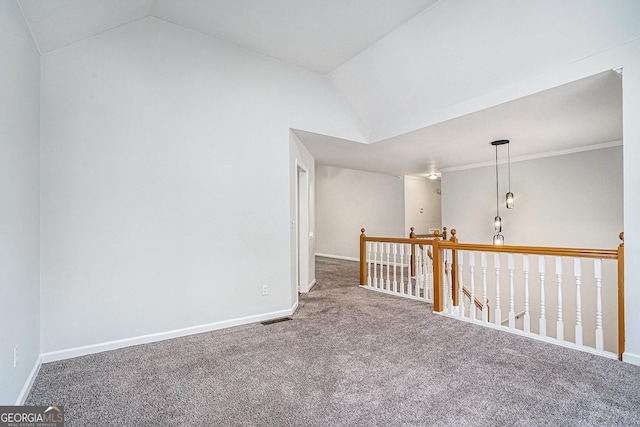 empty room featuring vaulted ceiling, crown molding, and carpet flooring