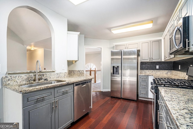 kitchen featuring appliances with stainless steel finishes, light stone counters, gray cabinets, and sink