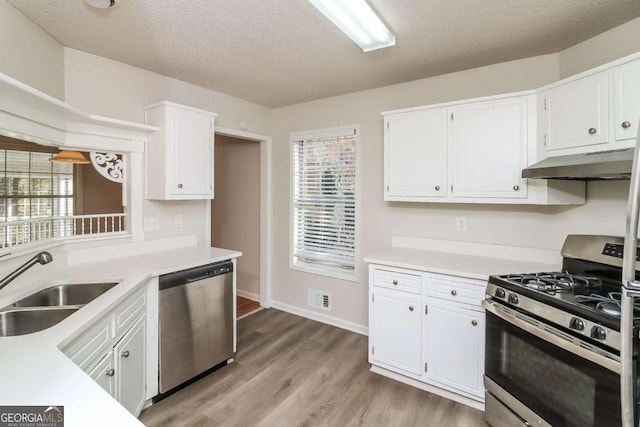 kitchen with white cabinets, sink, light hardwood / wood-style flooring, a textured ceiling, and stainless steel appliances