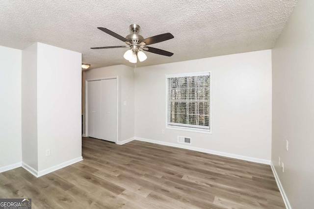 empty room featuring ceiling fan, wood-type flooring, and a textured ceiling