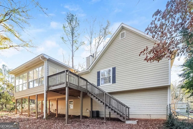 rear view of property with central air condition unit, a wooden deck, and a sunroom