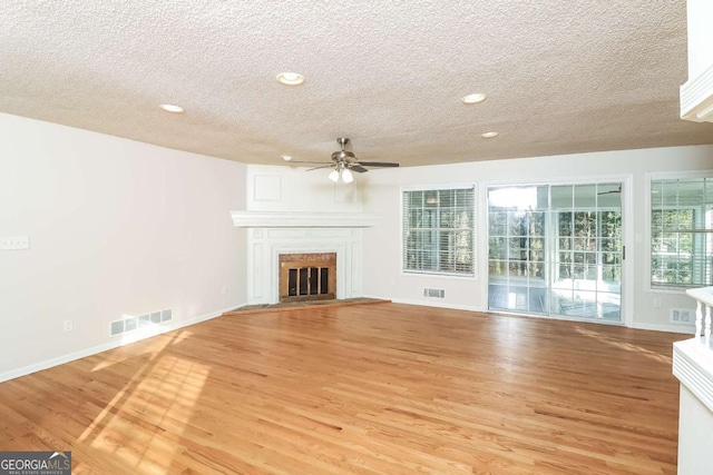 unfurnished living room with ceiling fan, light hardwood / wood-style flooring, and a textured ceiling