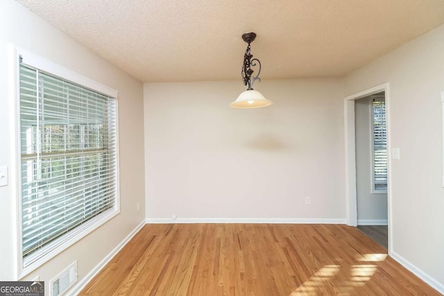 unfurnished dining area featuring a textured ceiling and hardwood / wood-style flooring