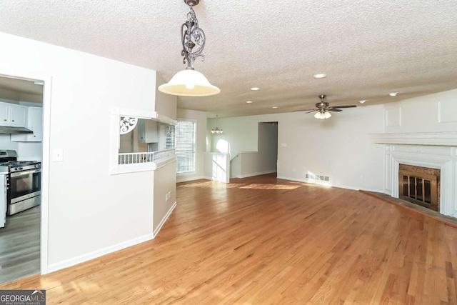 unfurnished living room with ceiling fan, light hardwood / wood-style floors, and a textured ceiling