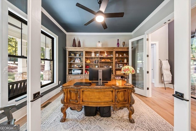 home office with ceiling fan, light wood-type flooring, crown molding, and french doors