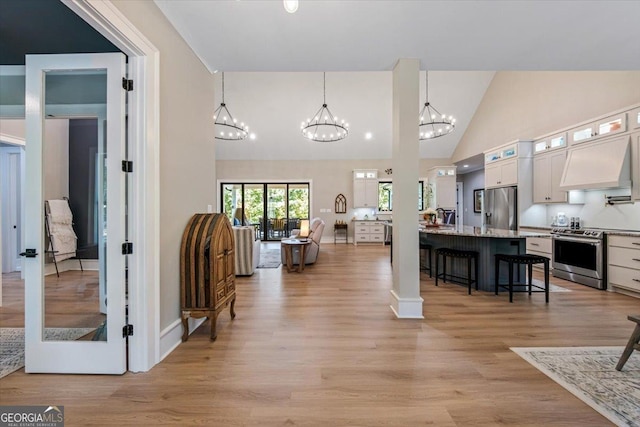 interior space with white cabinetry, pendant lighting, a breakfast bar, custom range hood, and appliances with stainless steel finishes