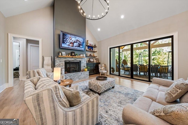 living room with a chandelier, a fireplace, high vaulted ceiling, and light hardwood / wood-style flooring