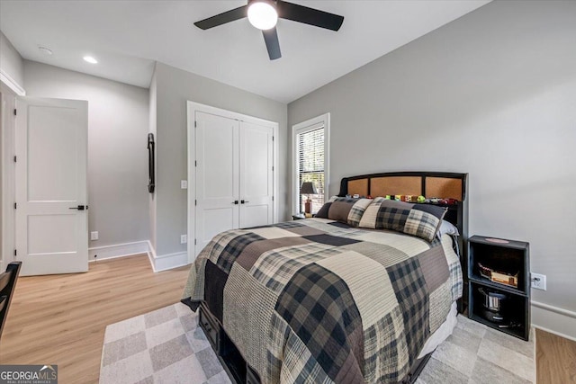 bedroom featuring light wood-type flooring, a closet, vaulted ceiling, and ceiling fan