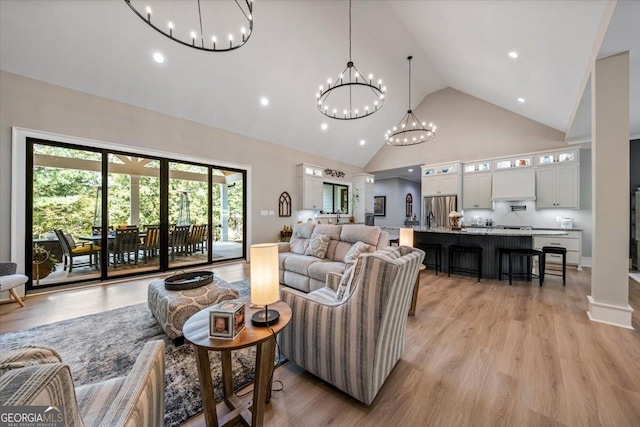 living room featuring light hardwood / wood-style floors, high vaulted ceiling, and a notable chandelier