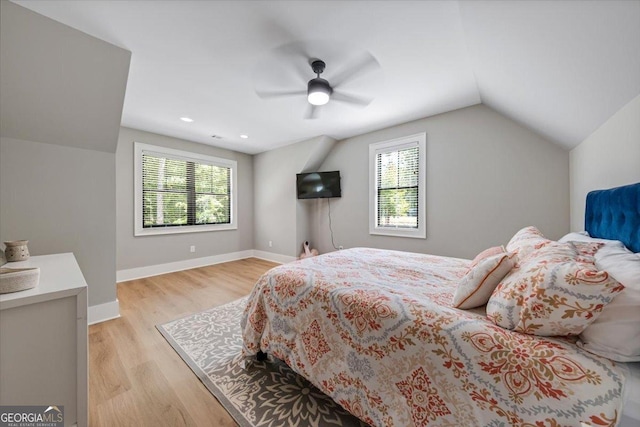 bedroom featuring multiple windows, light hardwood / wood-style floors, ceiling fan, and lofted ceiling