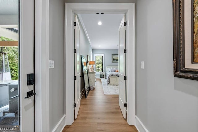 corridor with light hardwood / wood-style flooring and crown molding