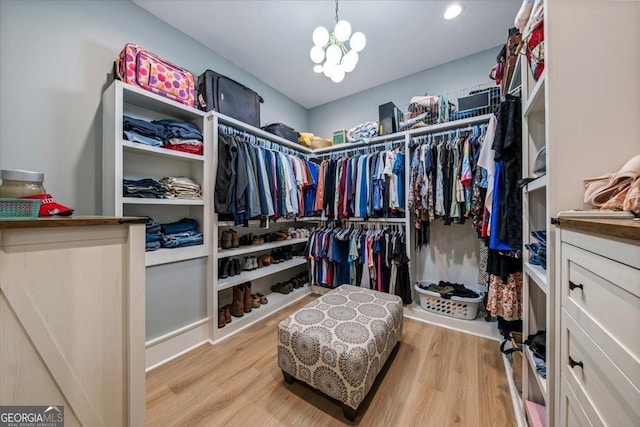 spacious closet with a notable chandelier and light wood-type flooring