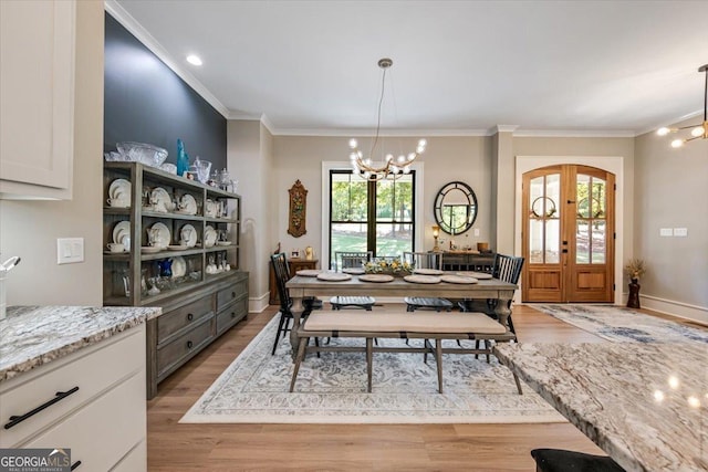 dining room featuring a chandelier, french doors, light hardwood / wood-style flooring, and ornamental molding