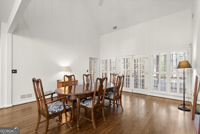 dining room featuring dark wood-type flooring, high vaulted ceiling, and french doors