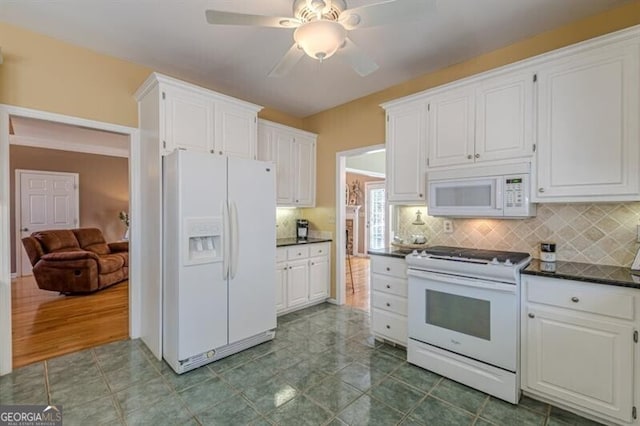 kitchen with decorative backsplash, dark countertops, white cabinetry, and white appliances