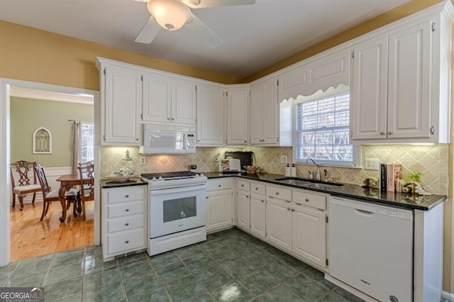 kitchen with dark countertops, ceiling fan, a sink, and white appliances
