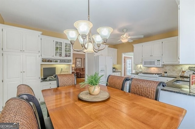 dining area featuring ceiling fan with notable chandelier