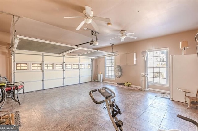 garage featuring a garage door opener, a ceiling fan, and baseboards